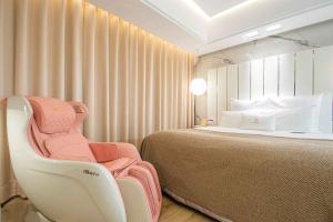 um quarto com uma cama e uma cadeira branca em Chao Motel em Taoyuan