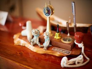 una mesa de madera con estatuillas de gatos y un reloj en 民宿さざんか en Okinawa City