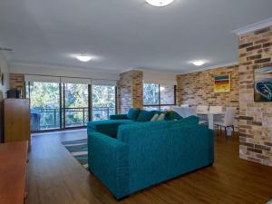 un soggiorno con divano blu e muro di mattoni di Bay Parklands 69 large unit with views pool tennis court and spa a Nelson Bay