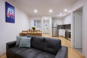 a living room with a couch and a kitchen at Airport Apartments by Vetroblu in Perth