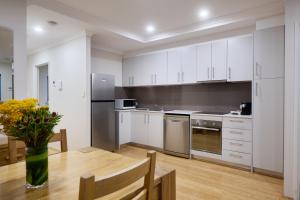 a kitchen with white cabinets and white appliances at Airport Apartments by Vetroblu in Perth