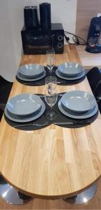 a wooden table with plates and wine glasses on it at le nid douillet de la gare centre ville de Lens in Lens