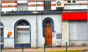 a building with a brown door and two windows at le nid douillet de la gare centre ville de Lens in Lens