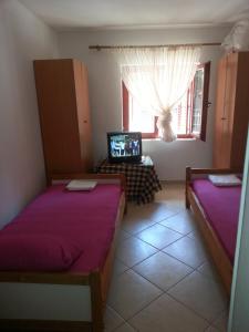 a room with two beds and a television in it at Apartments Nada in Utjeha