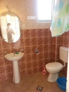 a man taking a picture of a bathroom with a toilet and sink at Apartments Nada in Utjeha