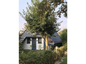 una casa blanca con un techo negro y un árbol en Ferienhaus Opi Huck, en Dorum-Neufeld