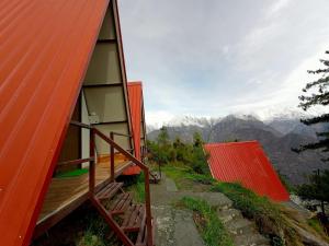 una pequeña casa con techo rojo en una montaña en Cottages Amid Mountains en Joshīmath