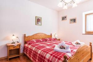 a bedroom with a bed with a red and white blanket at Agritur Alle Quattro Stagioni in Tonadico