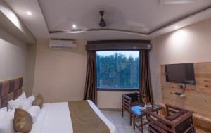 a bedroom with a bed and a large window at The Tattwaa Corbett Spa & Retreat in Rāmnagar