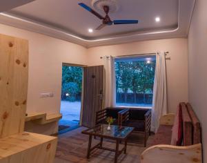 a living room with a ceiling fan and a table at The Tattwaa Corbett Spa & Retreat in Rāmnagar