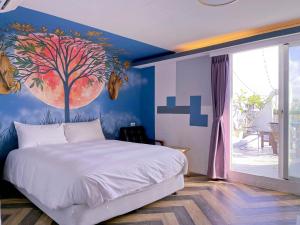 a bedroom with a bed with a tree painted on the wall at Deer Moon Hostel in Kenting