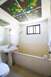 a bathroom with a sink and a toilet and a tub at Hejia Hot Spring Hotel in Ren'ai