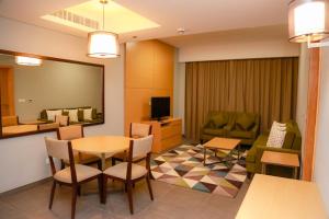 Habitación con mesa, sillas y sala de estar. en Ayla Ibri Hotel, en Ibri