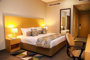 una habitación de hotel con una cama grande y una silla en Ayla Ibri Hotel, en Ibri