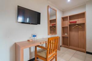 een kamer met een houten bureau en een televisie aan de muur bij Cihampelas Hotel 2 Mitra RedDoorz in Bandung