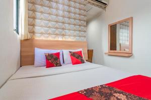 a bedroom with a bed with red and white pillows at Cihampelas Hotel 2 Mitra RedDoorz in Bandung