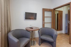 PalÃ¡rikovoにあるWellness a Relax centrum Palárikovoの椅子2脚とテーブル1台とテレビがある部屋