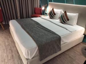 1 dormitorio con 1 cama grande con sábanas y almohadas blancas en Yogi Metropolitan Hotel en Navi Mumbai