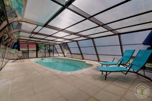 a patio with a pool with chairs and a roof at GITE MAEN ROCH in Val Couesnon