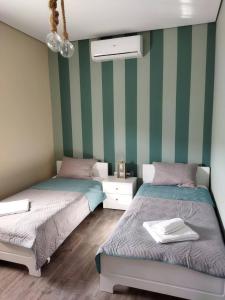 two beds in a room with green and white stripes at Tzoli Residence in Kalamaki Heraklion