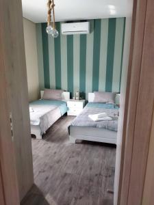 2 camas en una habitación con rayas verdes y blancas en Tzoli Residence, en Kalamaki