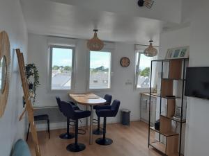 a dining room with a table and chairs and two windows at Studio calme 20m² à 500 mètres de la plage/ centre in Saint-Pierre-Quiberon