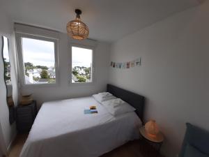 a bedroom with a white bed and two windows at Studio calme 20m² à 500 mètres de la plage/ centre in Saint-Pierre-Quiberon