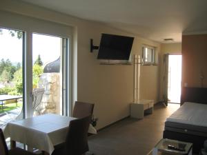 a living room with a table and a tv on the wall at Villa Burgblick in Annenheim