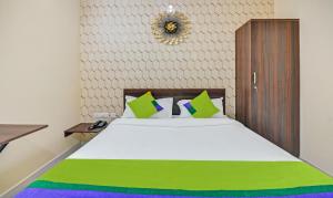 ein Schlafzimmer mit einem großen weißen Bett mit grünen und blauen Kissen in der Unterkunft Treebo Trend Everest Residency Tidel Park in Coimbatore