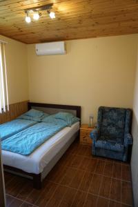 um quarto com uma cama e uma cadeira em FŰZFA VENDÉGHÁZ em Demjén