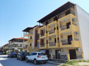 a yellow building with cars parked in front of it at Hotel Kosmas in Sarti