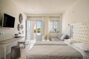 a hotel room with a bed, tv and a desk at El Greco Resort & Spa in Fira