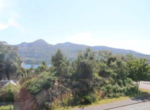 a road with trees and mountains in the background at Tulloch (2 Hamilton Place) in Kyle of Lochalsh