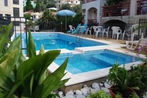 a swimming pool with a table and chairs next to a building at Apartments Srzentic in Petrovac na Moru