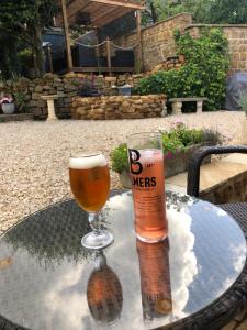 a glass of beer and a beer bottle on a table at Wisteria Cottage - Hillside Holiday Cottages, Cotswolds in Warmington +16 photos