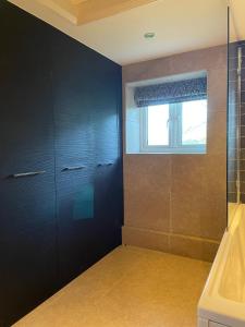 a bathroom with black cabinets and a window at Wisteria Cottage - Hillside Holiday Cottages, Cotswolds in Warmington