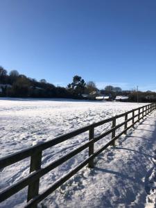 a fence in a field covered in snow at Wisteria Cottage - Hillside Holiday Cottages, Cotswolds in Warmington