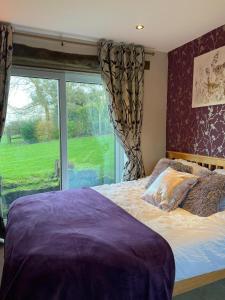 a bedroom with a bed and a large window at Wisteria Cottage - Hillside Holiday Cottages, Cotswolds in Warmington