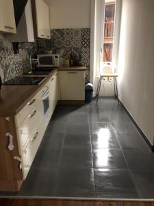 a kitchen with white cabinets and a tile floor at Appartement de charme avec parking et terrasse in Besançon