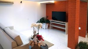 uma sala de estar com uma televisão e uma parede de tijolos em GUINZA no Balneário Camboriú