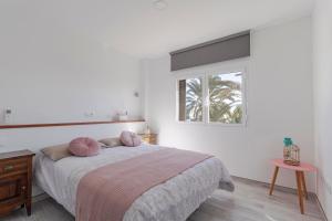 a bedroom with a bed with pink pillows on it at Costa Luz Sirens Beach in Los Pocillos