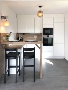 a kitchen with white cabinets and a table with two chairs at Meerwunder in Wangerland
