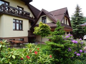 a house with a garden in front of it at Olimp pokoje i apartamenty in Szczyrk