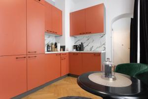 une cuisine avec des armoires orange et une table noire dans l'établissement Old Town Vienna, à Vienne