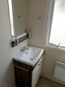 Un baño con lavabo, espejo y ventana. en Bungalow cosy à Onzain avec terrasse & piscine partagée, en Onzain