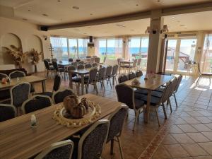 ein Restaurant mit Holztischen und -stühlen und dem Meer in der Unterkunft Hotel Nautilos in Sozopoli