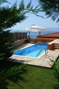 una piscina con sombrilla y el océano en Erofili Villas en Lourdata