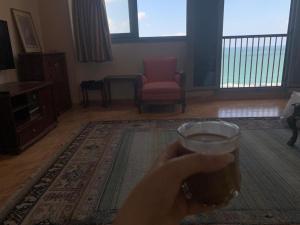 a person holding a glass of beer in a living room at Panoramic Sea View Flat miami FAMILY ONLY شقة بانورما بشاطئ ميامي الاسكندرية عائلات فقط in Alexandria