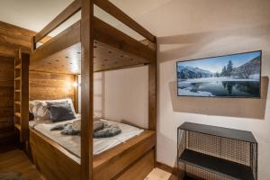 una camera con letto a castello e TV a parete di Apartment Ophite Méribel - by EMERALD STAY a Les Allues