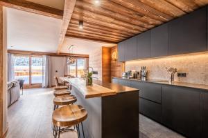 a kitchen with black cabinets and wooden ceilings at Apartment Ophite Méribel - by EMERALD STAY in Les Allues